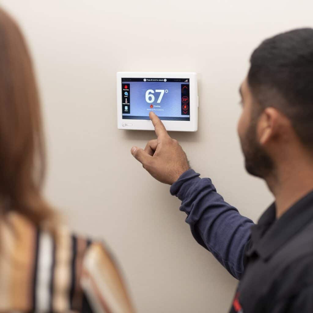 HVAC Technician showing a Indianapolis homeowner her newly installed smart thermostat.