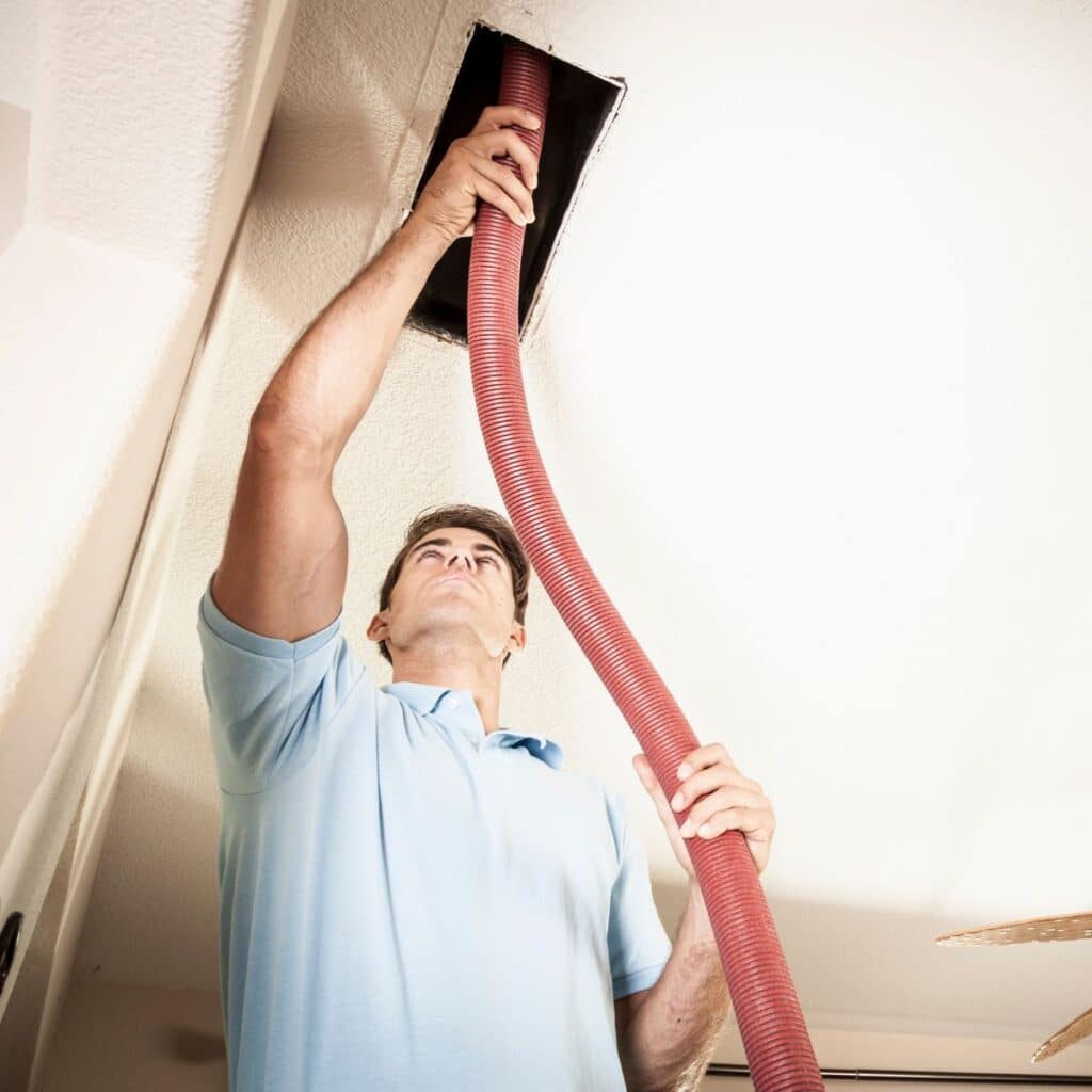 HVAC Technician vacuuming out a dirty air duct in an Indianapolis home.